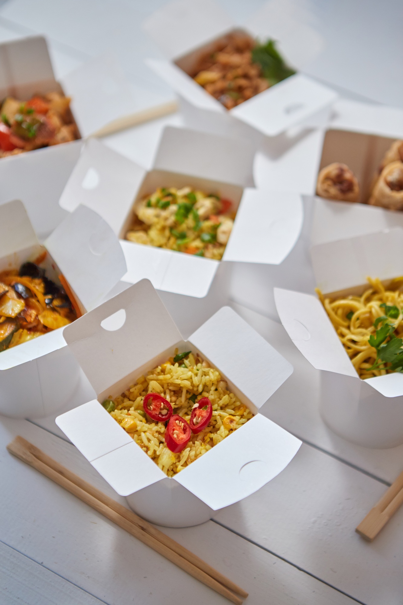 Asian take away or delivery food concept. Paper boxes placed on white wooden table