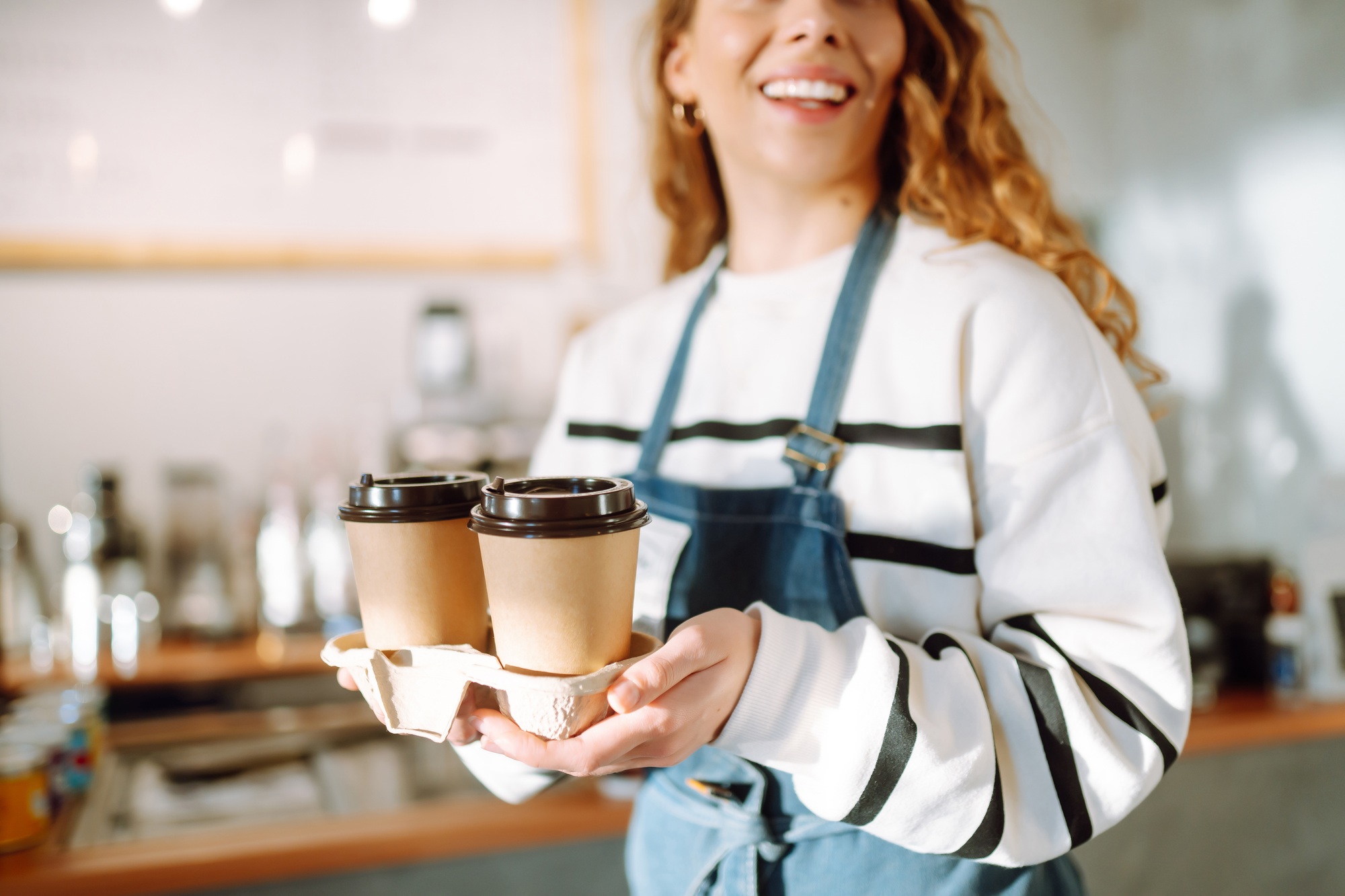 Take-away coffee. Barista girl holding take away coffee at the cafe shop. Takeaway food.