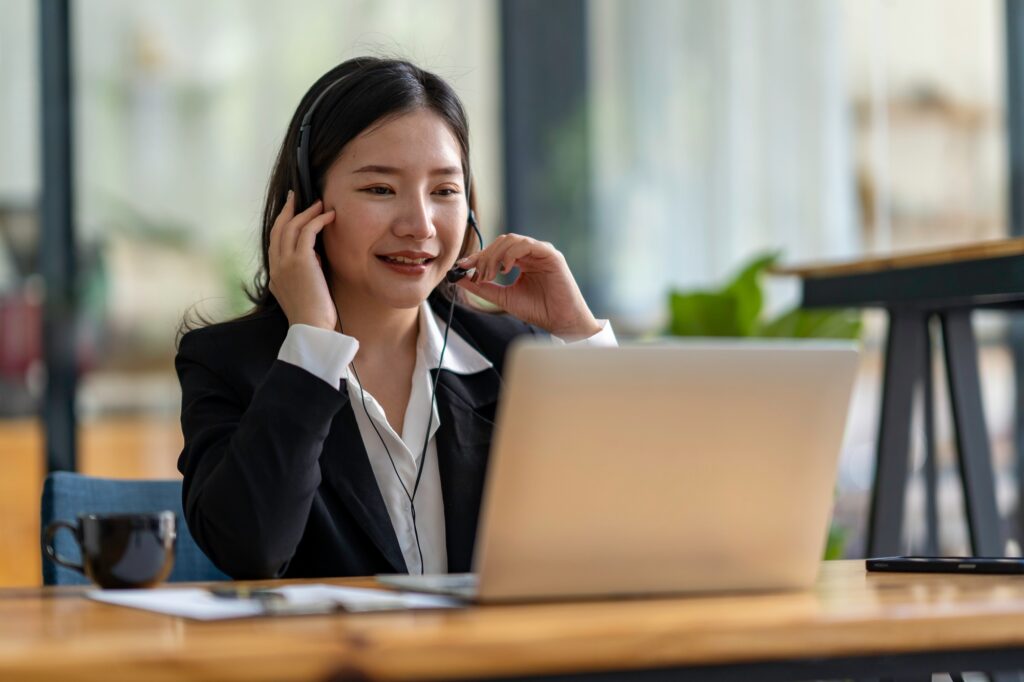 Happy Asian woman sitting in the office and video conference with a business partner on a laptop. Co