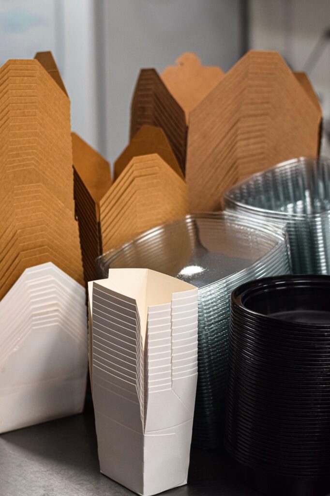 Stacks of paper and plastic disposable take out containers on a restaurant shelf