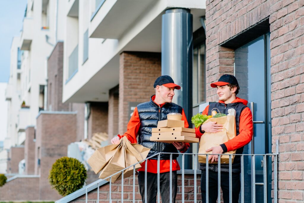 Why Are Pizza Boxes Square? 4 Two delivery men holding pizza box, take-out food containers